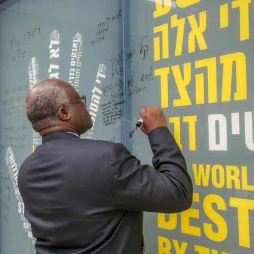 אדם משאיר חותמו על קירות מייצג השואה - "תעשיית השנאה"
